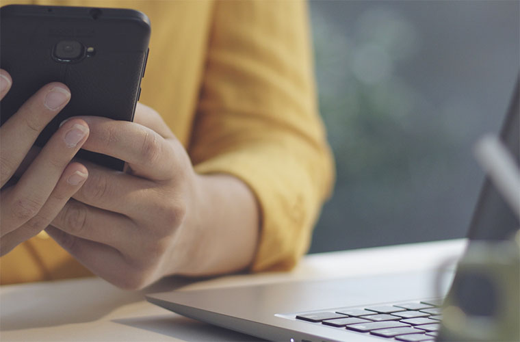 Woman sitting at desk in the office and sending messages with her smartphone